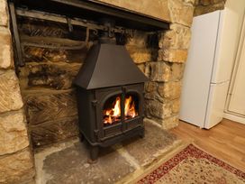 A living room with a fireplace and refrigerator at 5 Hollins Cottages in Whitby