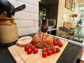 A kitchen with wine, cheese, bread, and tomatoes on a cutting board at 5 Hollins Cottages Whitby
