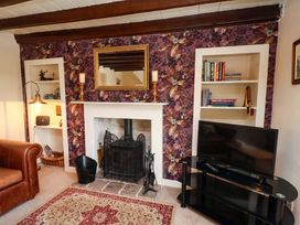 A living room with a fireplace and shelves at 5 Hollins Cottages in Whitby