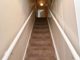 A staircase with a handrail and light fixture at 5 Hollins Cottages in Whitby