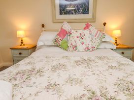 A bedroom with a floral bedspread and lamps at 5 Hollins Cottages Whitby