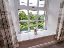 A window with a flower vase and curtains at 5 Hollins Cottages in Whitby