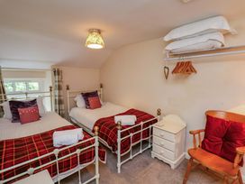A bedroom with two beds and a chair at 5 Hollins Cottages in Whitby