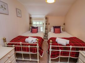 A bedroom with two beds and a window at 5 Hollins Cottages in Whitby