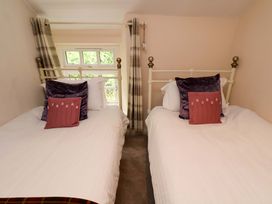 A bedroom with two beds and windows at 5 Hollins Cottages in Whitby