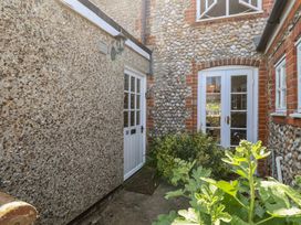 An outdoor area with a door, window, and pebble wall at Pebble in Blakeney, Norfolk