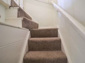 A staircase with carpeted steps and a handrail at Pebble in Blakeney, Norfolk