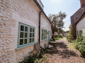 An outdoor area with a table and chairs beside a pathway at Buttercup, Blakeney, Norfolk