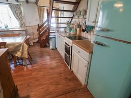 A kitchen with a refrigerator, stove, and dining table at Buttercup in Blakeney, Norfolk
