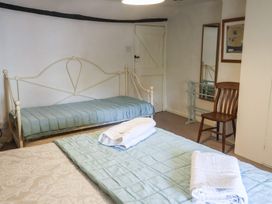 A bedroom with two beds and a chair at Buttercup in Blakeney, Norfolk