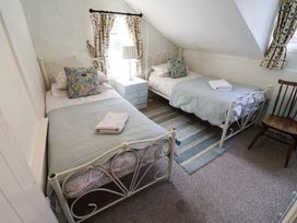 A bedroom with two beds and a bedside table at Buttercup in Blakeney, Norfolk
