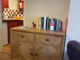 A bookcase with books and a kettle in a living room at The Bittern in Blakeney, Norfolk
