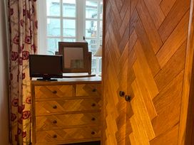 A bedroom with a wardrobe, dresser, television, and mirror at The Bittern in Blakeney, Norfolk