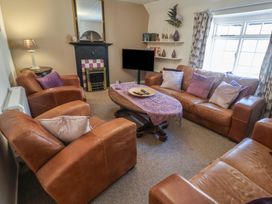 A living room with sofa, coffee table, and television at The Plover in Blakeney, Norfolk