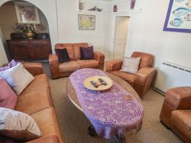 A living room with brown leather sofas and a coffee table at The Plover in Blakeney, Norfolk