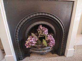 A fireplace with artificial flowers in a metal basket at The Plover in Blakeney, Norfolk