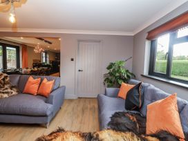 A living room with sofas and a plant at Holly Farm in Brantham