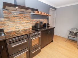 A kitchen with an oven and stove with a shelf and high chair at Holly Farm in Brantham