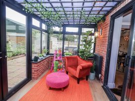 A conservatory with a red chair and plants at Holly Farm in Brantham