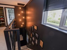 A hallway with a staircase and photographs on the wall at Holly Farm in Brantham