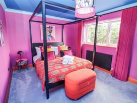 A bedroom with a four-poster bed and a window at Holly Farm in Brantham