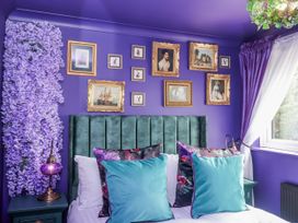 A bedroom with a green bed and purple walls at Holly Farm in Brantham
