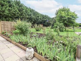 A garden with flower beds and a patio at Holly Farm in Brantham