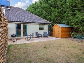 A garden with chairs and table next to a shed at Holly Farm in Brantham