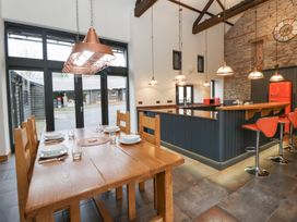 A kitchen with a dining table and bar stools at The Barn at Sunny Barn in Brecon