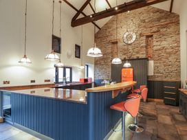 A kitchen with a stone wall and bar stools at The Barn at Sunny Barn in Brecon