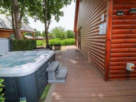 An outdoor area with a hot tub next to a wooden deck at Sunnyside Lodge Thorpe-On-The-Hill