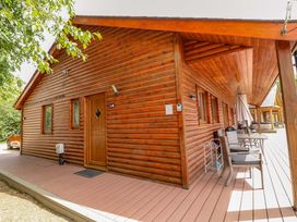 A wooden cabin with a porch and outdoor furniture at Sunnyside Lodge in Thorpe-On-The-Hill