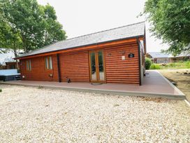 An outdoor view of a log cabin with gravel area at Sunnyside Lodge in Thorpe-On-The-Hill