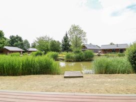An outdoor area with cabins and a pond at Sunnyside Lodge in Thorpe-On-The-Hill
