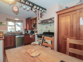 A kitchen with wooden cabinets and appliances at Vine Cottage in Alderton