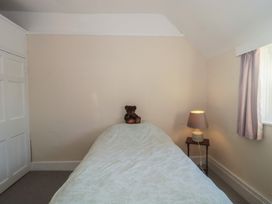 A bedroom with a bed and a teddy bear on it at Vine Cottage in Alderton