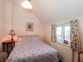 A bedroom with a bed and nightstand at Vine Cottage in Alderton