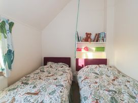 A bedroom with two beds and a shelf with books at Vine Cottage in Alderton