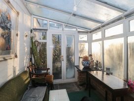A conservatory with a couch and table at Vine Cottage Alderton