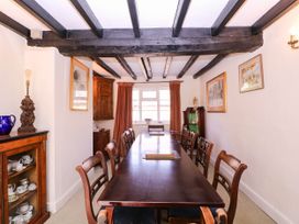 A dining room with a long table and chairs at Vine Cottage in Cheltenham