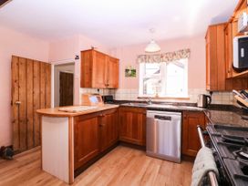 A kitchen with wooden cabinets and a dishwasher at Vine Cottage in Cheltenham