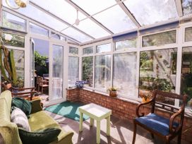 A conservatory with a sofa and a table at Vine Cottage in Cheltenham