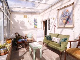 A conservatory with seating and a table at Vine Cottage in Cheltenham