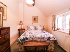 A bedroom with a bed and a lamp at Vine Cottage in Cheltenham