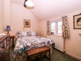 A bedroom with a bed, nightstand, and paintings at Vine Cottage in Cheltenham