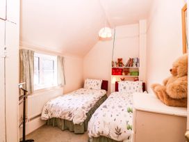A bedroom with two beds and a bookshelf at Vine Cottage in Cheltenham