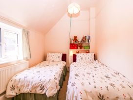 A bedroom with twin beds and a shelf with books at Vine Cottage in Cheltenham
