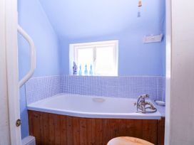 A bathroom with a bathtub and window at Vine Cottage in Cheltenham