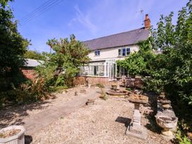 A garden with a house and conservatory at Vine Cottage in Cheltenham