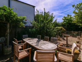 A garden with a wooden table and chairs at Vine Cottage Cheltenham